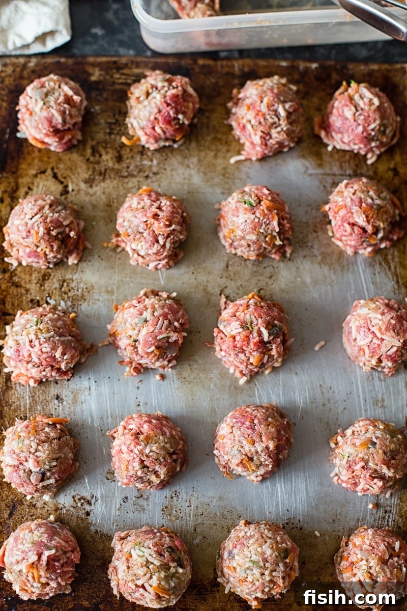 Raw porcupine meatballs, shaped and ready for browning, arranged neatly on a baking sheet.