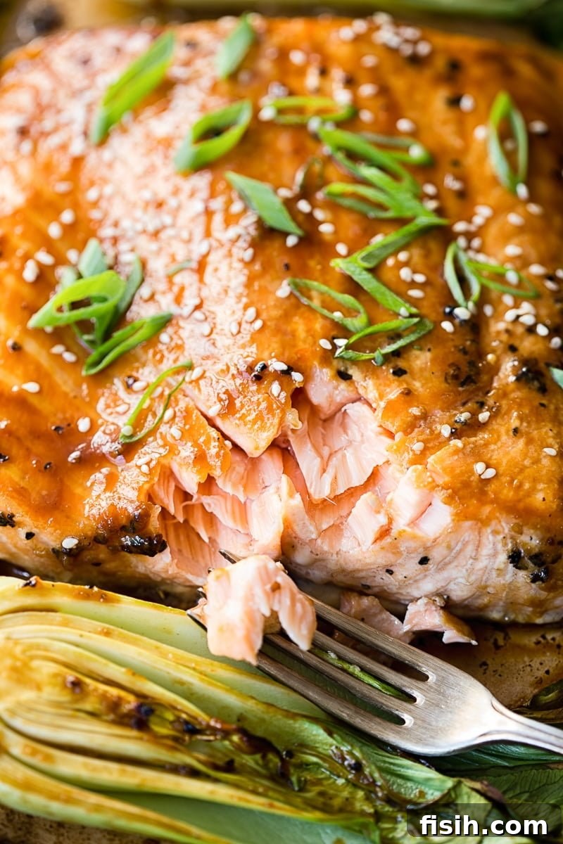 Served plate of teriyaki salmon with bok choy, garnished with spring onions and sesame seeds.
