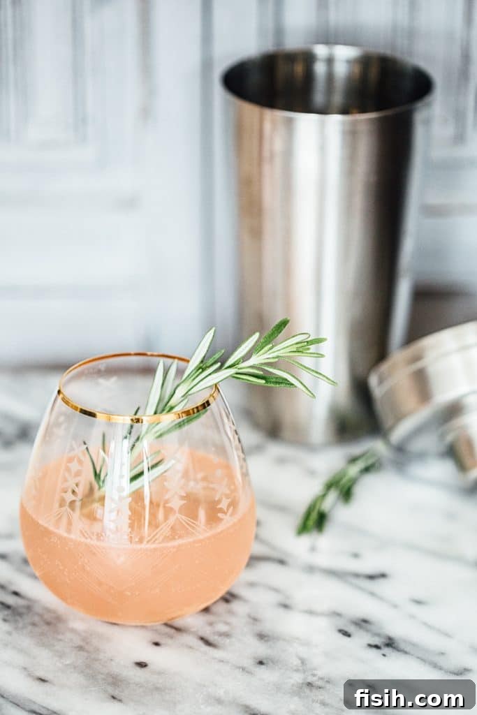 Elevate Your Gin and Tonic Three Ways 5 Side shot of G&T with Rosemary and Grapefruit with cocktail shake behind