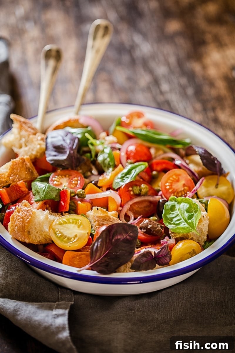 Rustic Tuscan Bread Salad 2 A vibrant Panzanella Salad overflowing with juicy red and yellow tomatoes, chunks of crusty bread, and fresh green basil leaves in a rustic bowl.
