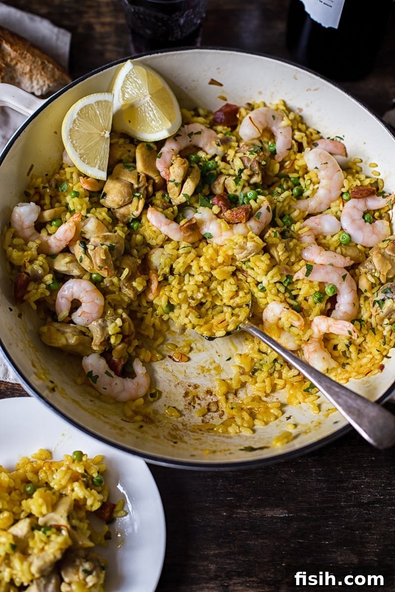 Spanish rice in a while pan with a spoon in it, a small white plate filled with the dish next to it.