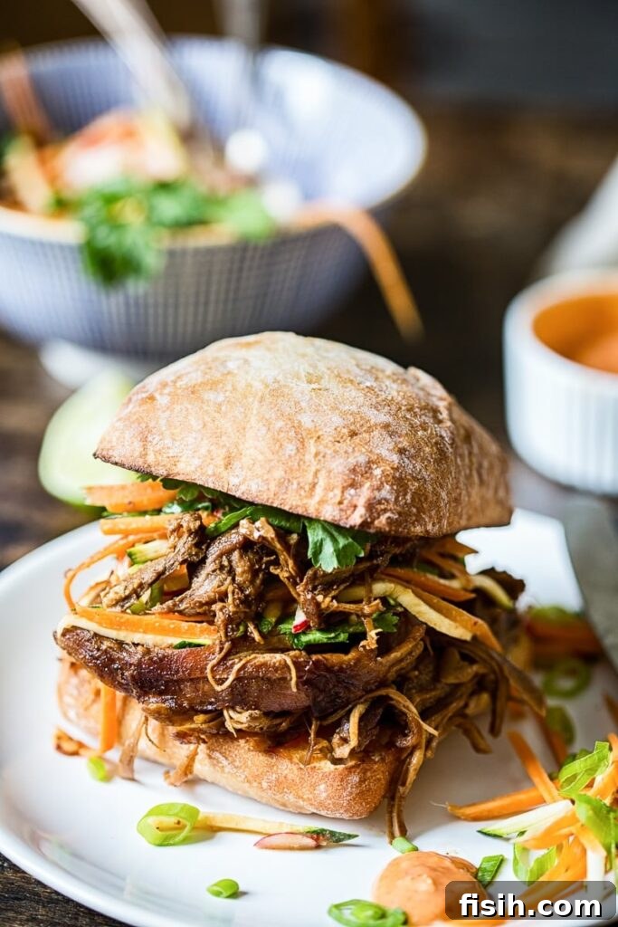 Fusion Pulled Pork Sandwiches with Zesty Root Vegetable Slaw 2 Asian pulled pork buns with carrot, zucchini and radish slaw on a plate