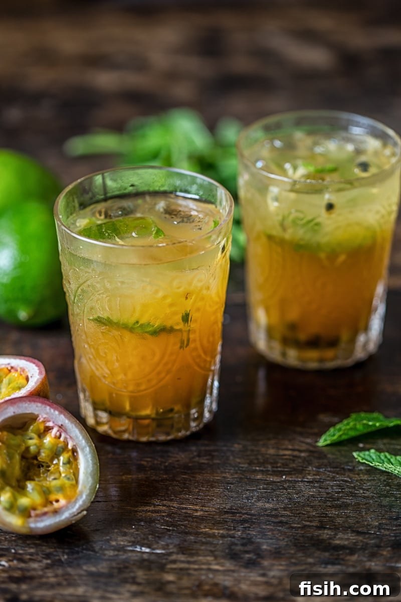 A frosty glass of Passion Fruit Mojito garnished with a lime wedge and mint sprig