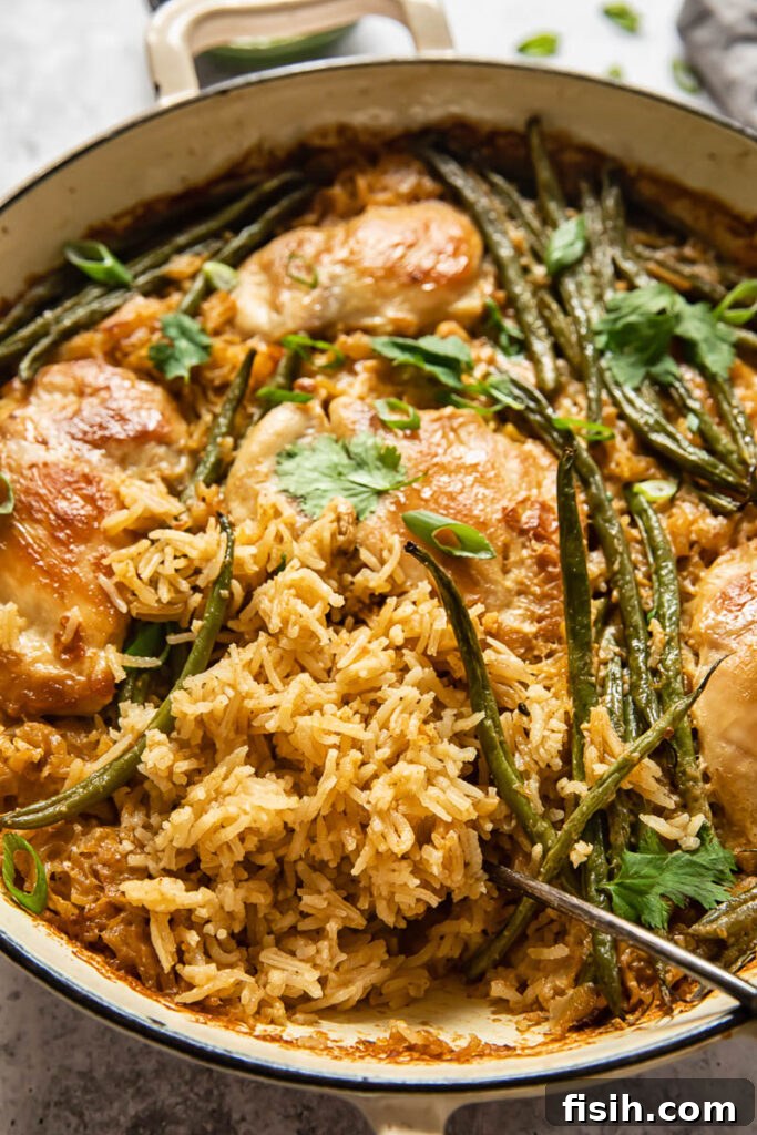 Golden-brown coconut chicken and rice with vibrant green beans, served in a white baking dish, ready for a delicious meal.