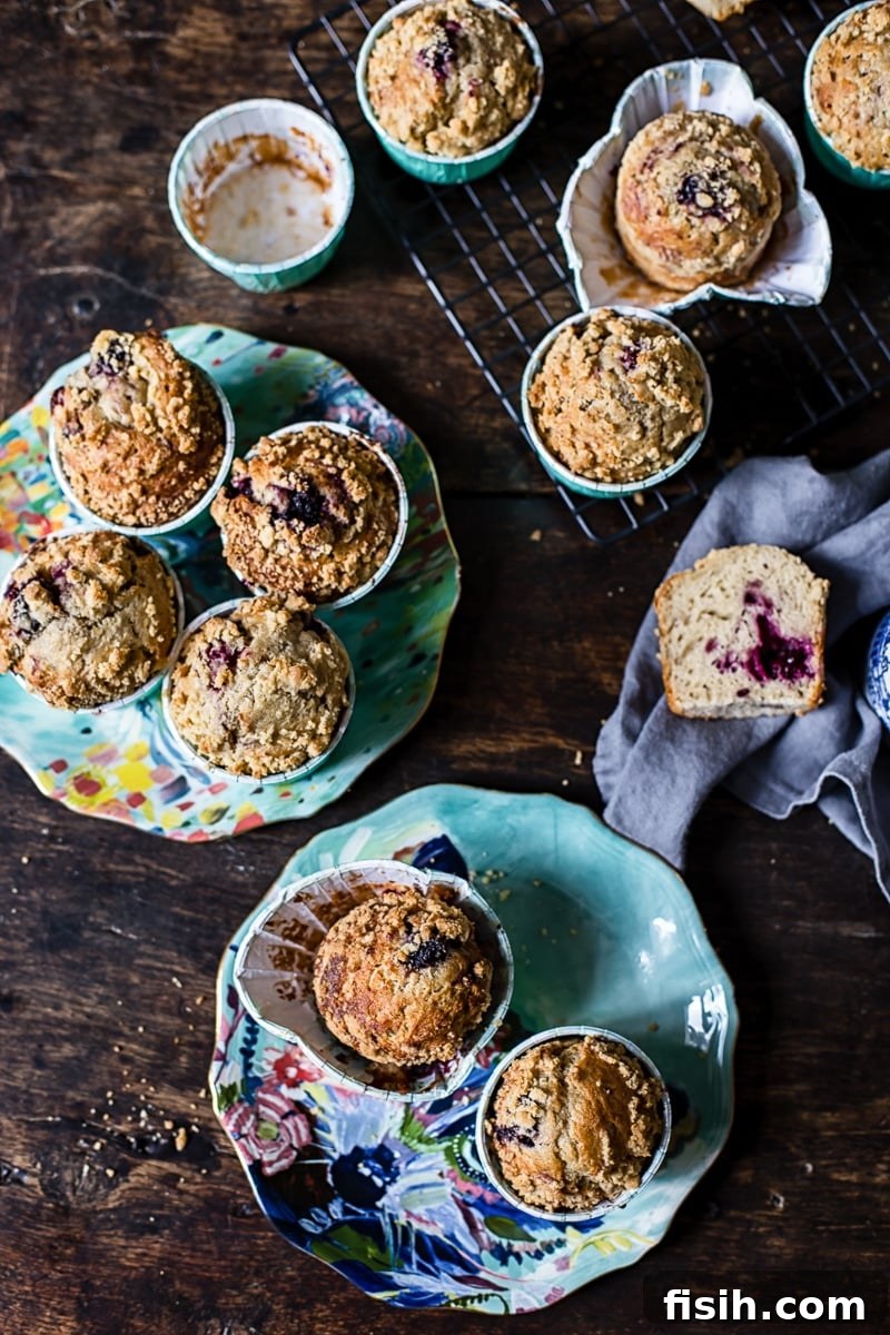 Gourmet Blackberry Burst Muffins 5 A stunning spread of Bakery Style Blackberry Muffins, showcasing their golden tops, streusel crumble, and the inviting peek of juicy blackberries, arranged on a cooling rack.