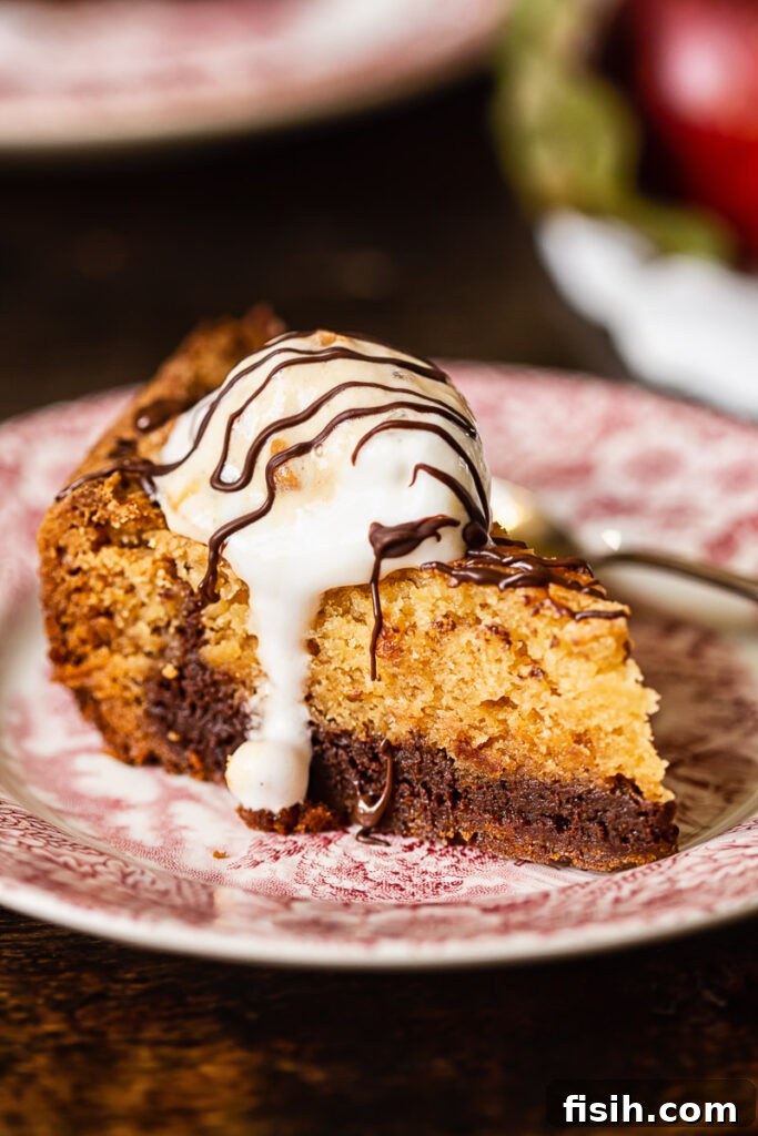 Irresistible Slow Cooker Chocolate Butterscotch Cookie Bars 6 A single piece of slow cooker chocolate butterscotch cookie bar on a plate, generously topped with a scoop of vanilla ice cream, emphasizing its warm and inviting presentation.