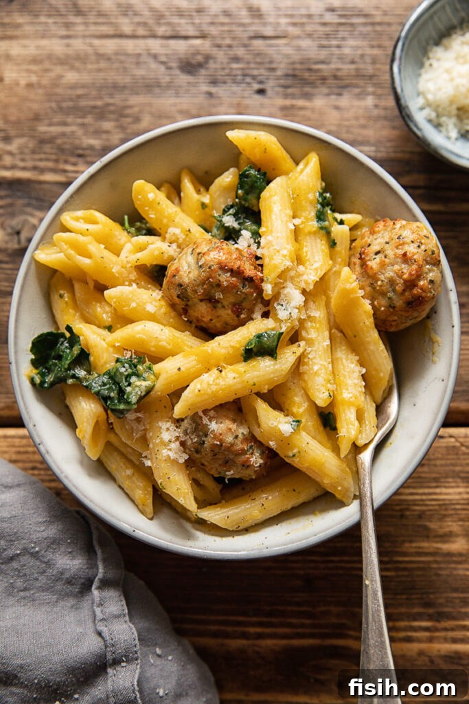 top down view with penne pasta, sausage meatballs, and creamy pumpkin sauce garnished with herbs