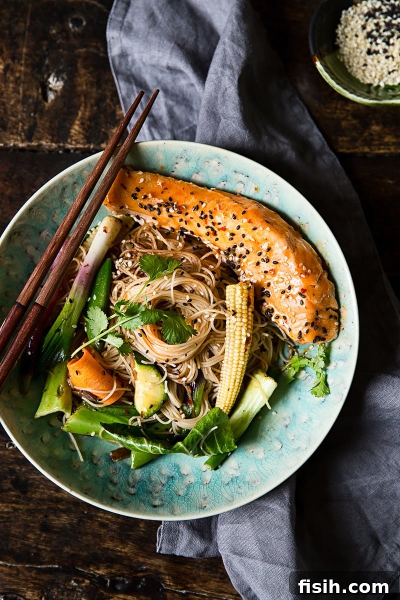 An overhead view of a vibrant Chilli Salmon Mee Goreng dish, showcasing the beautifully arranged fried noodles, colorful vegetables, and tender salmon.