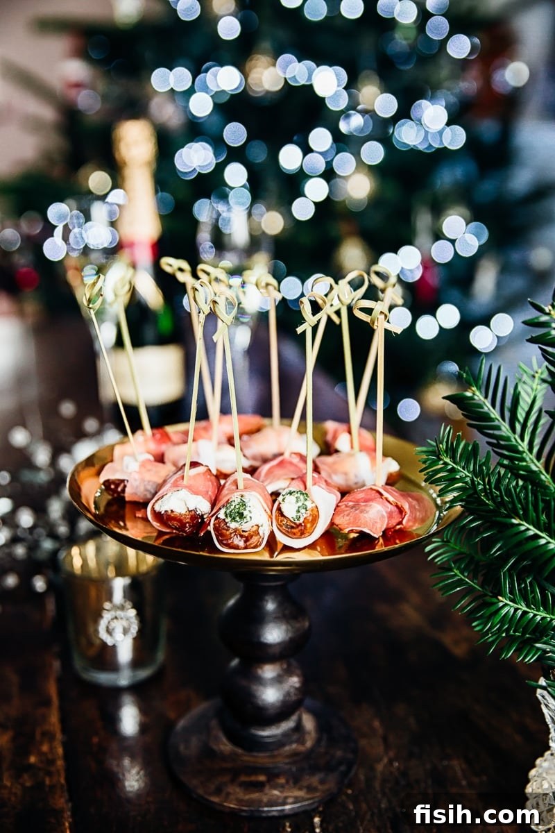 Herby Cheese Stuffed Dates Wrapped in Prosciutto on a platter with Christmas lights in the background