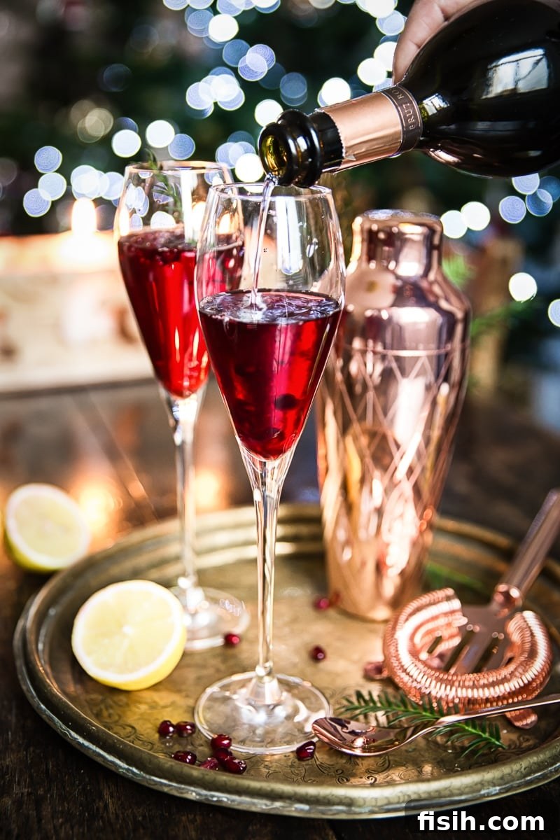 Champagne being poured into a glass of Pomegranate French 75, creating a beautiful bubbly effect