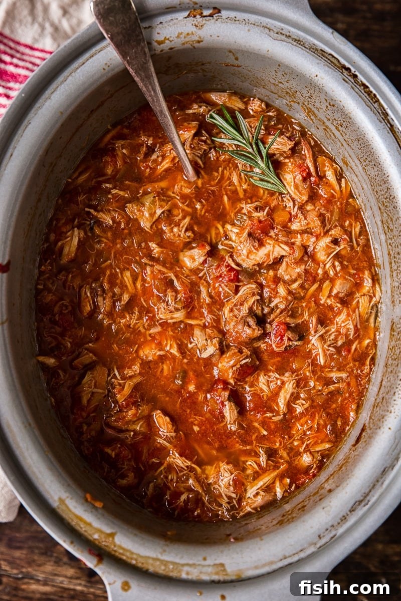 Braised Venetian Chicken Ragu Pasta 3 Overhead view of a slow cooker filled with the bubbling Venetian Chicken Ragu, garnished with a sprig of fresh rosemary, simmering to perfection.