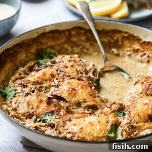 Side view of a pan with the spiced chicken thighs with spoon in the broth