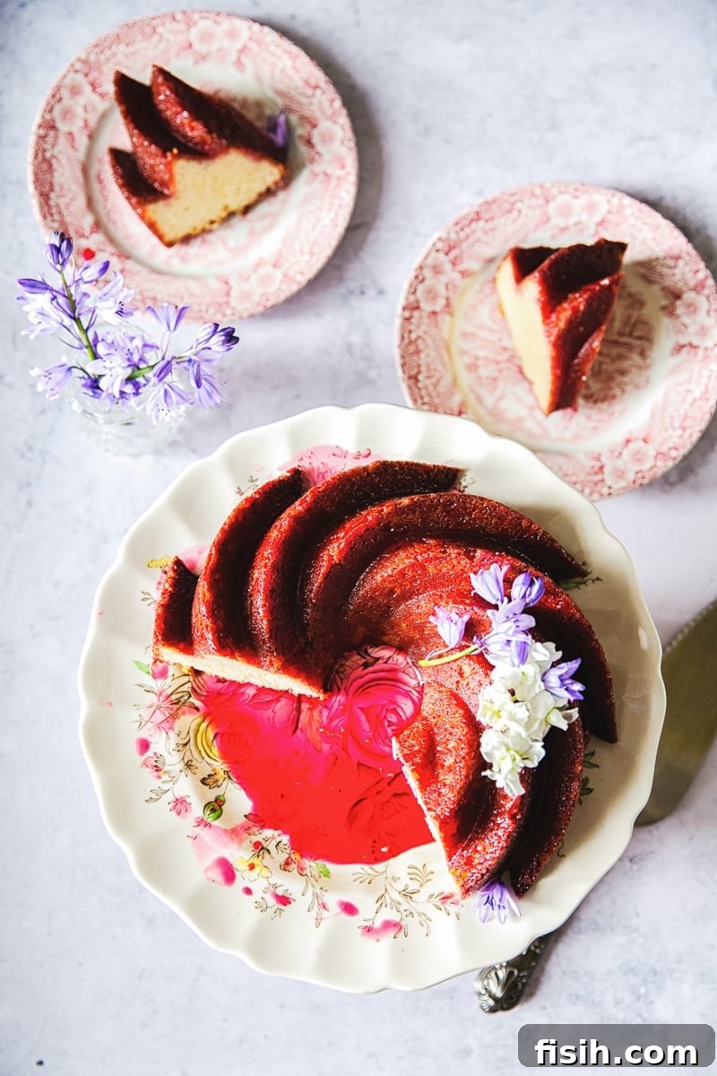 Vibrant blackberry glaze being drizzled generously over a slice of moist lemon ricotta cake, showcasing its rich ruby color and tantalizing texture.