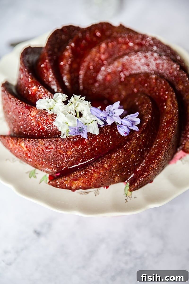 A whole Lemon Ricotta Bundt Cake topped with rich blackberry glaze, garnished with fresh blackberries and lemon slices, ready for serving.