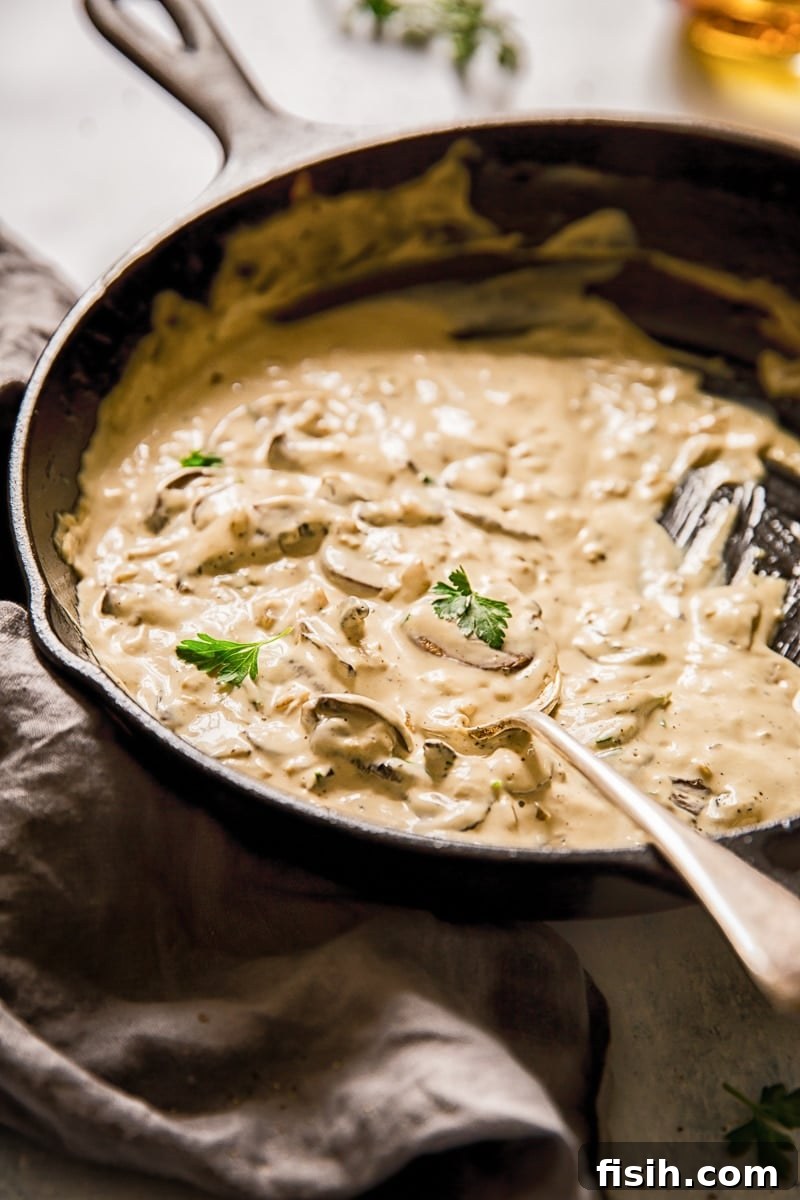 Side view of a spoon in a pan with luxurious cognac sauce and sautéed mushrooms, ready to serve