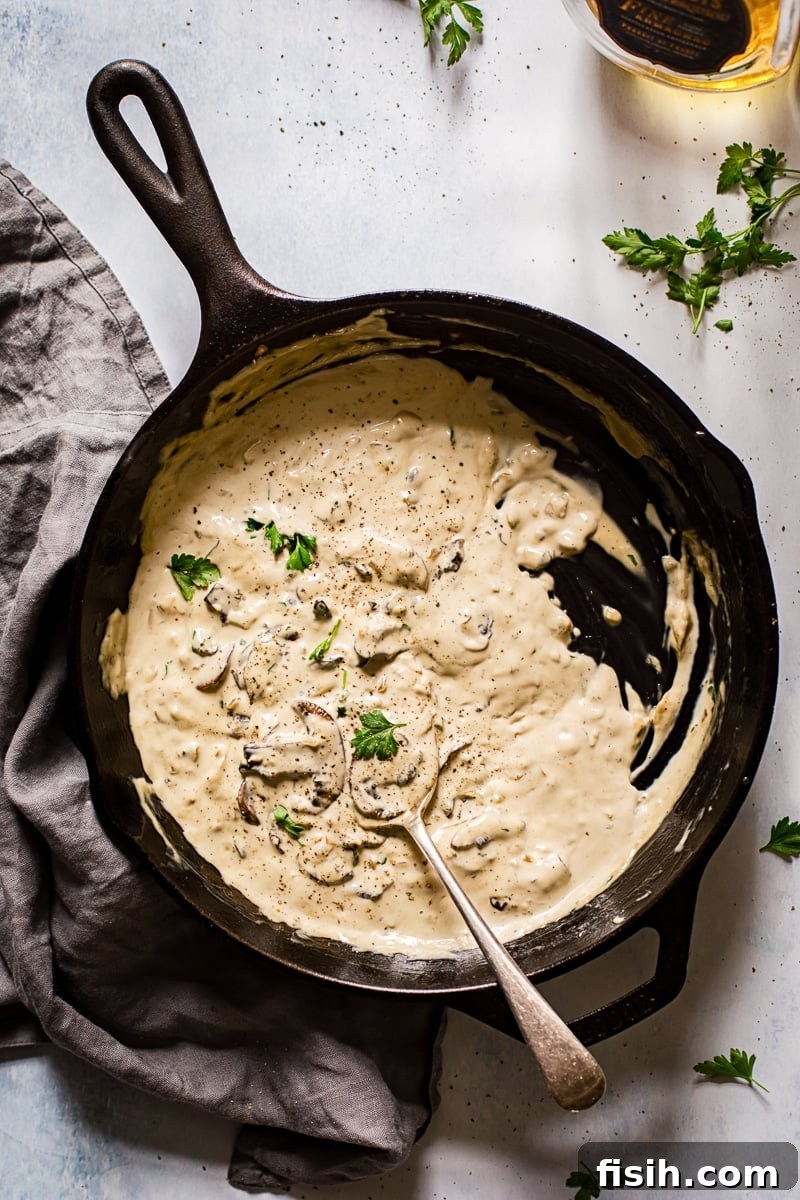 Top down view of creamy mushroom steak sauce simmering in a cast iron pan, highlighting its rich texture