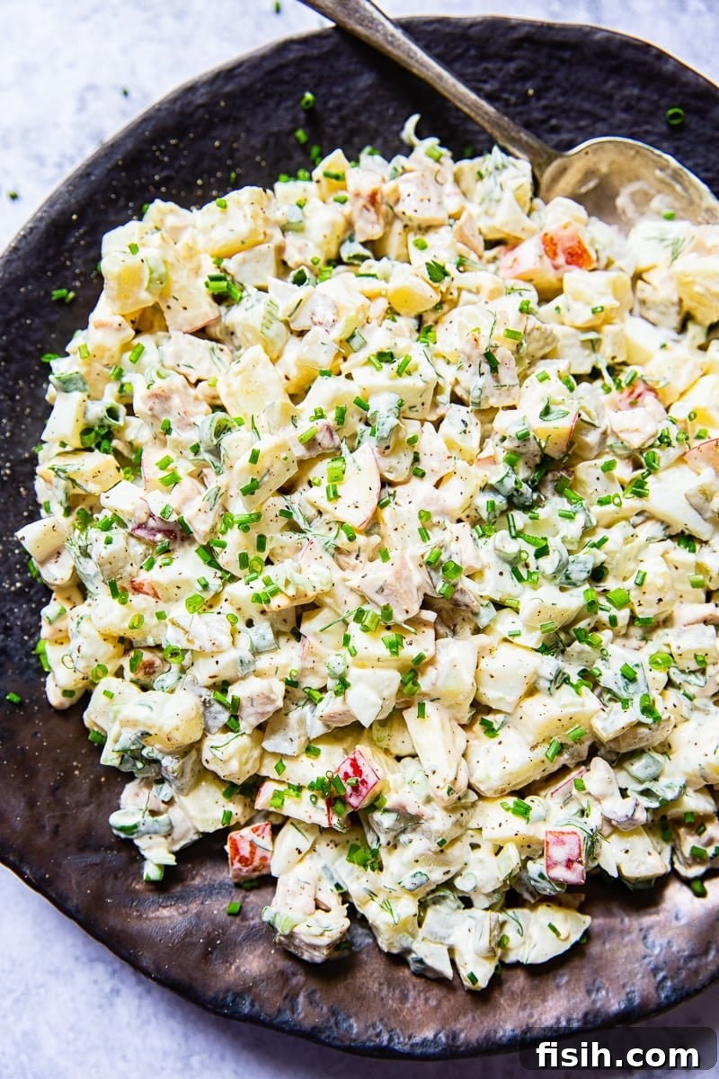 Top-down view of a generously portioned Russian salad Olivier, garnished with fresh herbs.