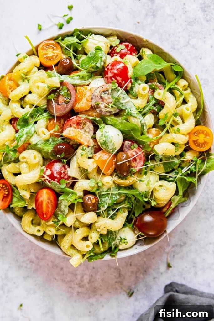 Top down view of a vibrant Green Goddess Pasta Salad, garnished with fresh herbs.