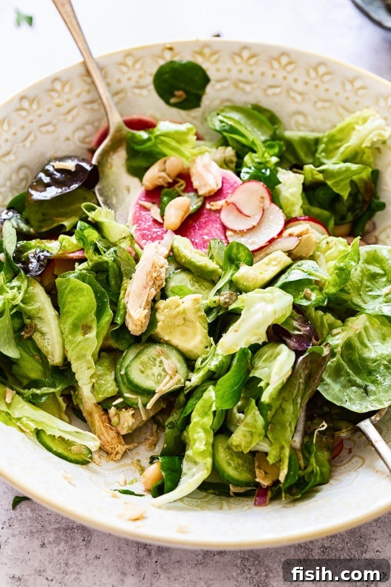 A bowl filled with crisp lettuce and thinly sliced radishes, with a spoon ready for serving