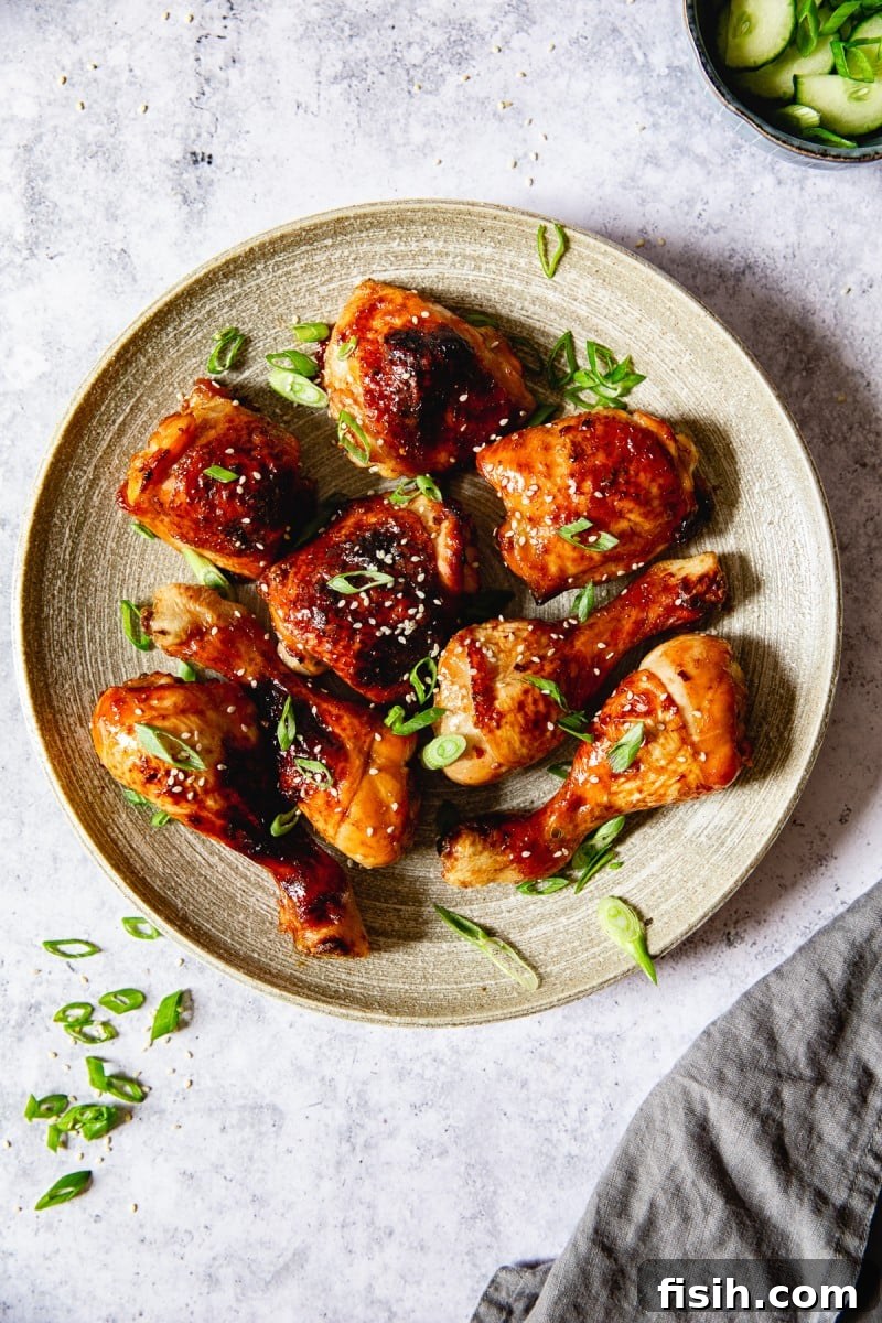 Top down view of beautifully cooked sticky Asian chicken thighs and legs, generously sprinkled with vibrant green onions.