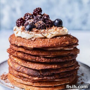 A stack of buckwheat pancakes, topped with whipped cream and berries, ready to be served for a delightful breakfast.