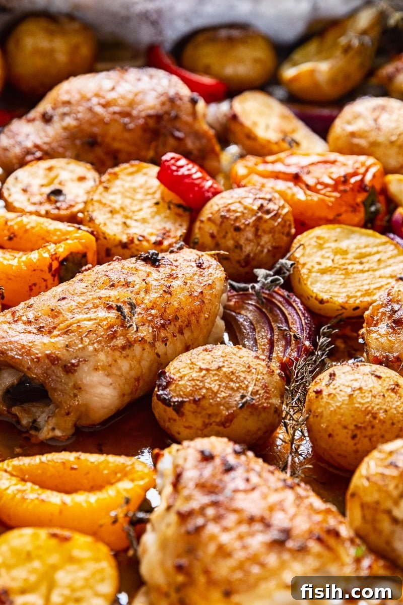 Close-up shot highlighting the beautifully roasted potatoes and chicken thighs in the pan