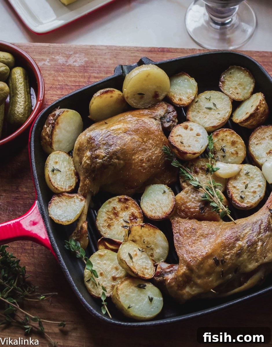 Top down view of cooked duck confit and roasted potatoes in a pan, ready to serve