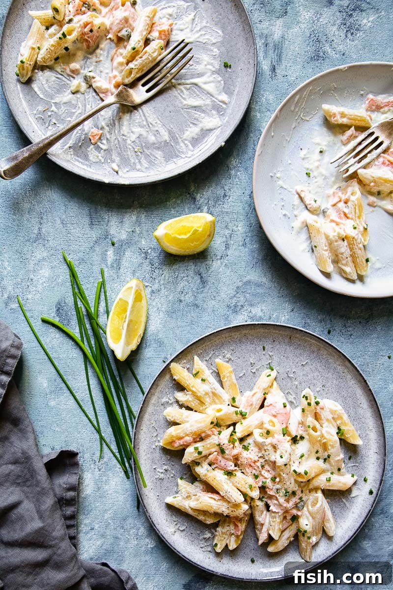 Top down view of two plates of pasta with smoked salmon, ready to be served