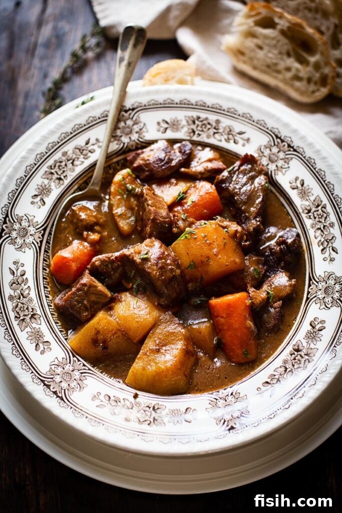 A steaming bowl of traditional Irish Beef Stew garnished with fresh herbs, ready to be served.