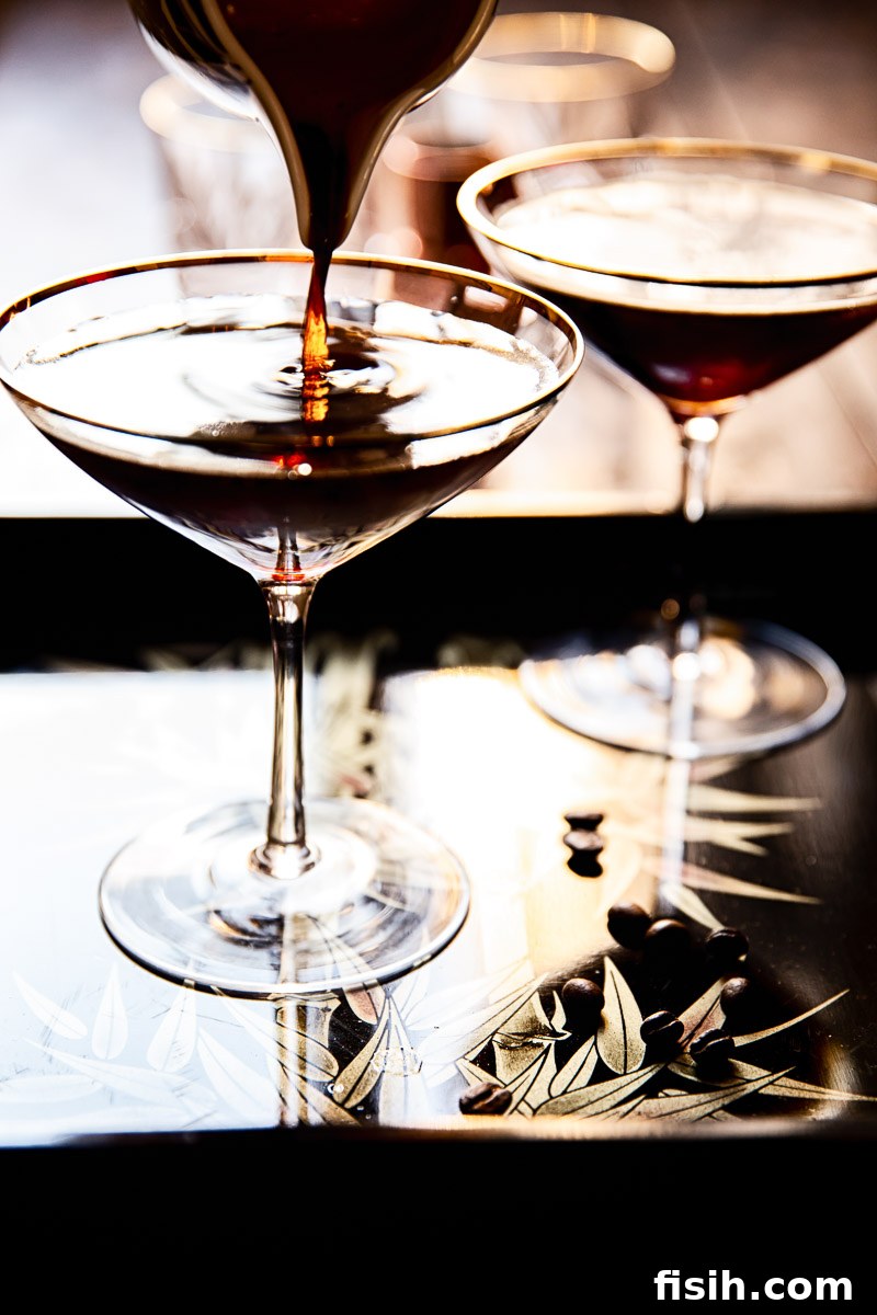 An Espresso Martini being poured into a martini glass, showing the foam forming on top.