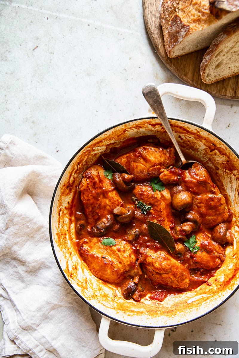 A top-down view of Chicken Chasseur served in a pan with crusty bread on the side, ready to be enjoyed.