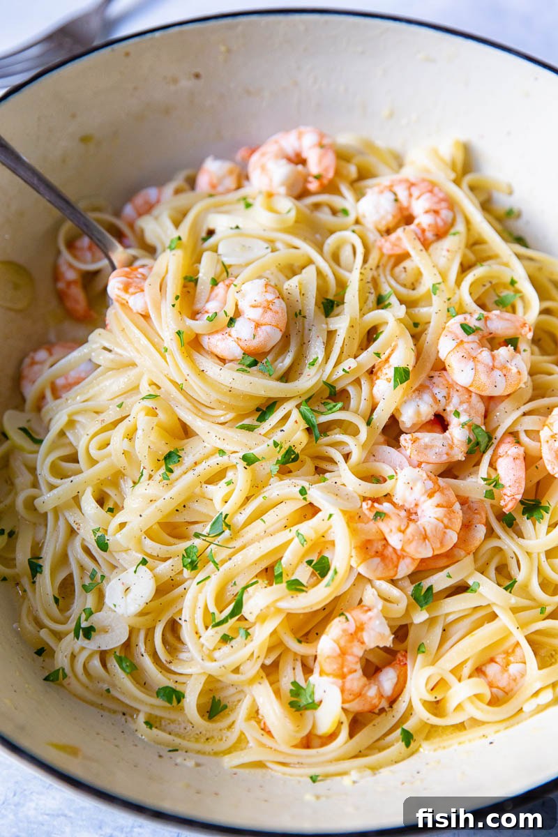 Shrimp Scampi Linguine served in a rustic cast iron pan with a wooden spoon, showcasing the rich garlic butter sauce coating the pasta.