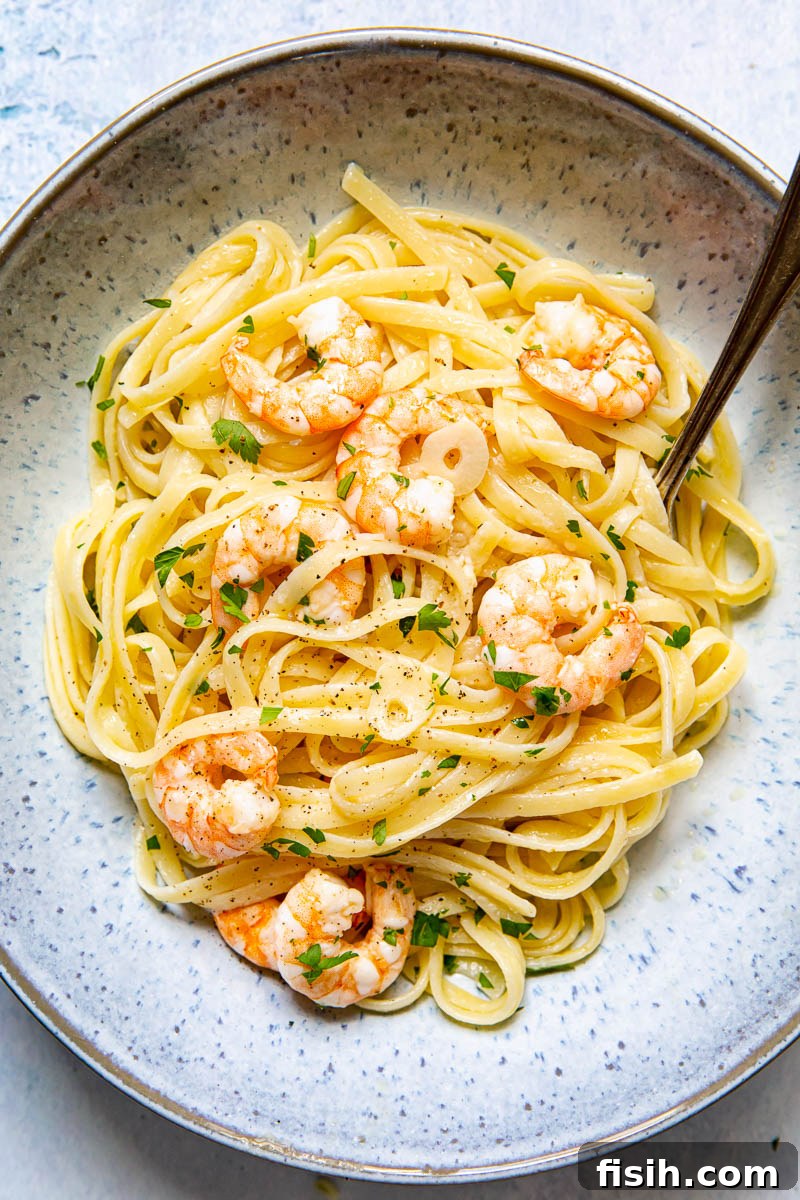 A vibrant blue bowl filled with Shrimp Scampi Linguine, twirled around a fork, ready to be enjoyed.