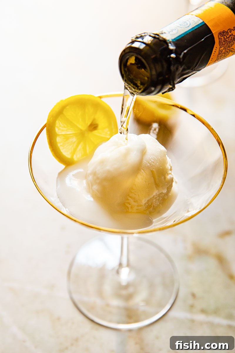 A bottle pouring crisp Prosecco into a chilled cocktail glass containing lemon sorbet and a lemon slice.
