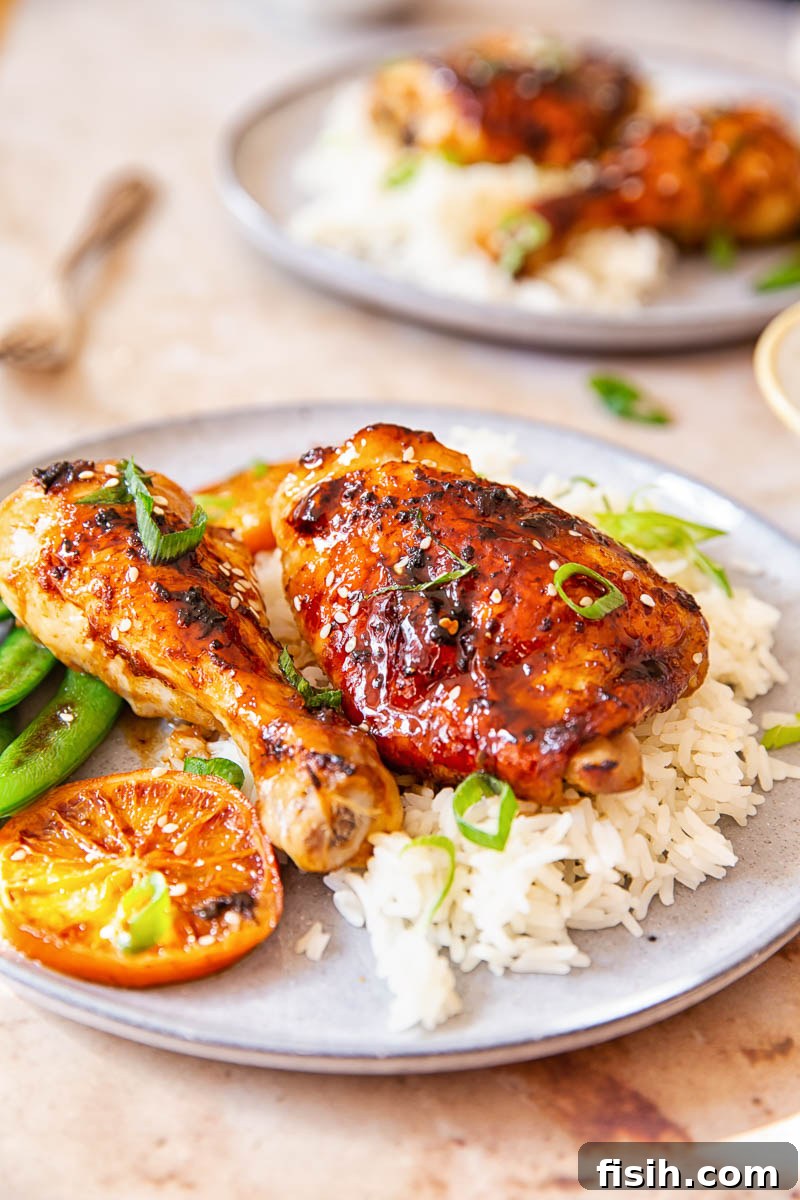 Sweet and Sticky Oven-Baked Chicken Thighs and Drumsticks 6 Honey Soy Chicken sprinkled with green onion and sesame seeds over white rice.