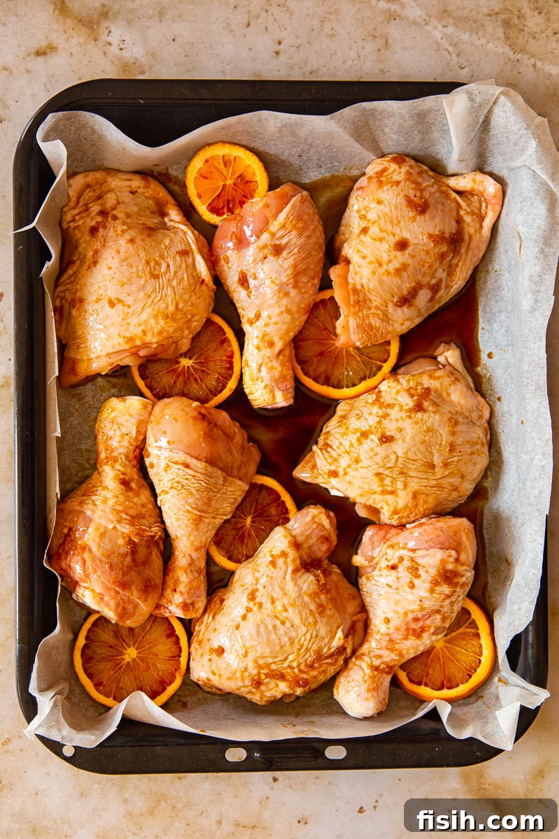 Sweet and Sticky Oven-Baked Chicken Thighs and Drumsticks 7 Unbaked honey soy chicken in roasting pan with orange slices