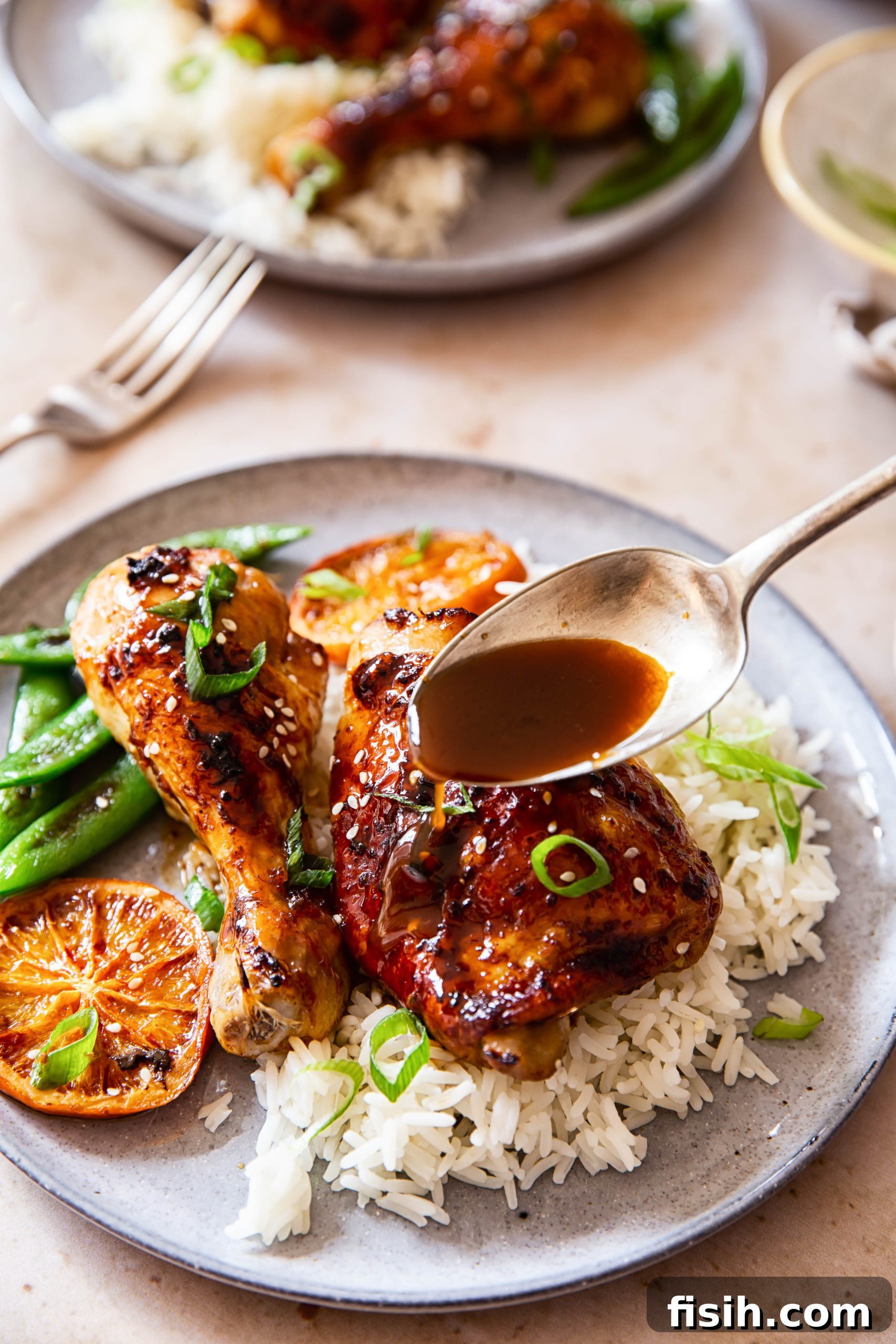 Sweet and Sticky Oven-Baked Chicken Thighs and Drumsticks 8 Honey Soy Chicken sprinkled with green onion and sesame seeds over white rice, close-up