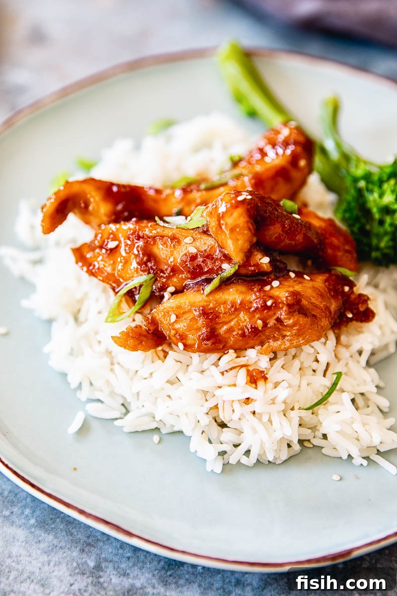Shoyu chicken on white rice with broccoli, garnished with green onions and sesame seeds