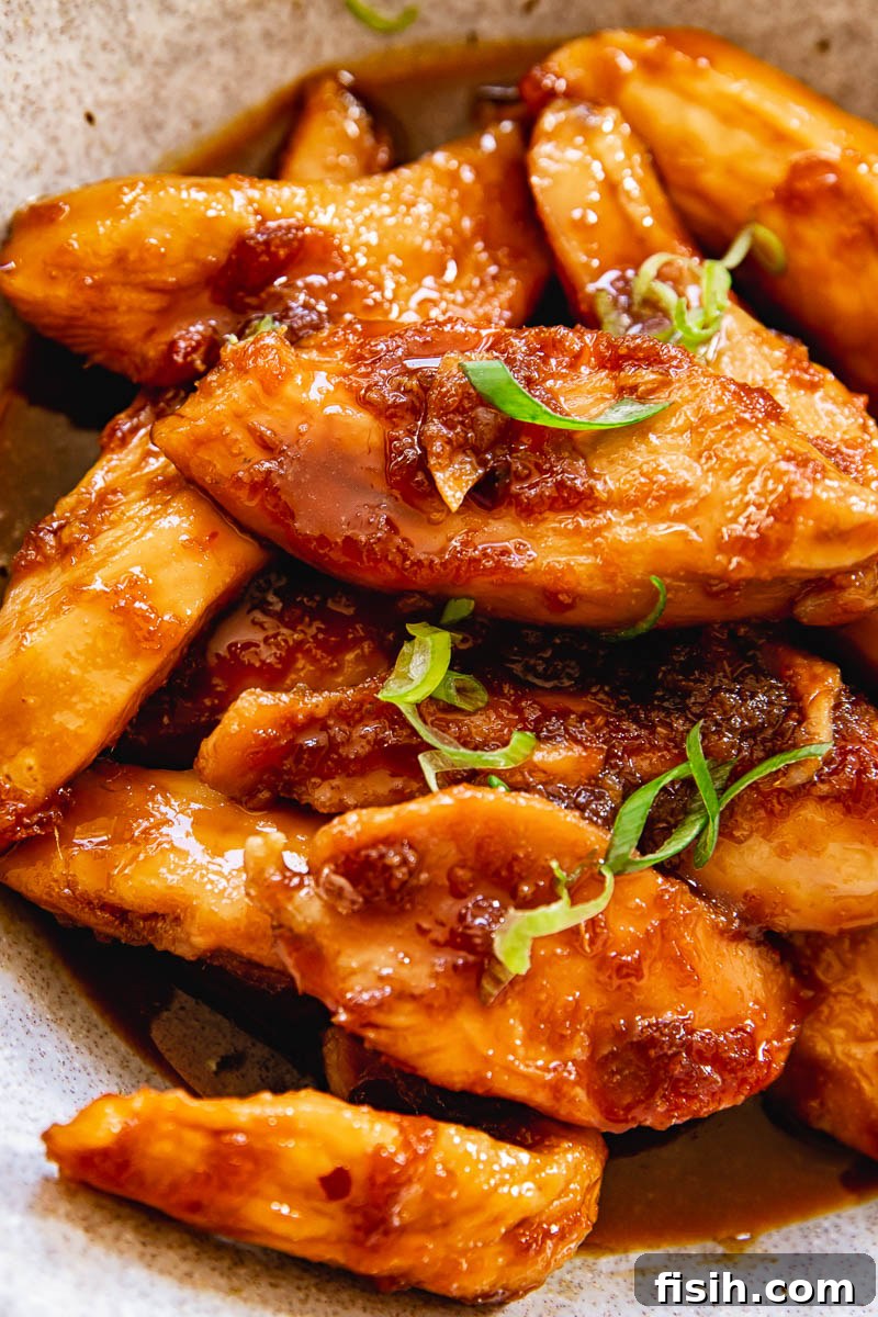 Close up of shoyu chicken sprinkled with sliced green onions and sesame seeds