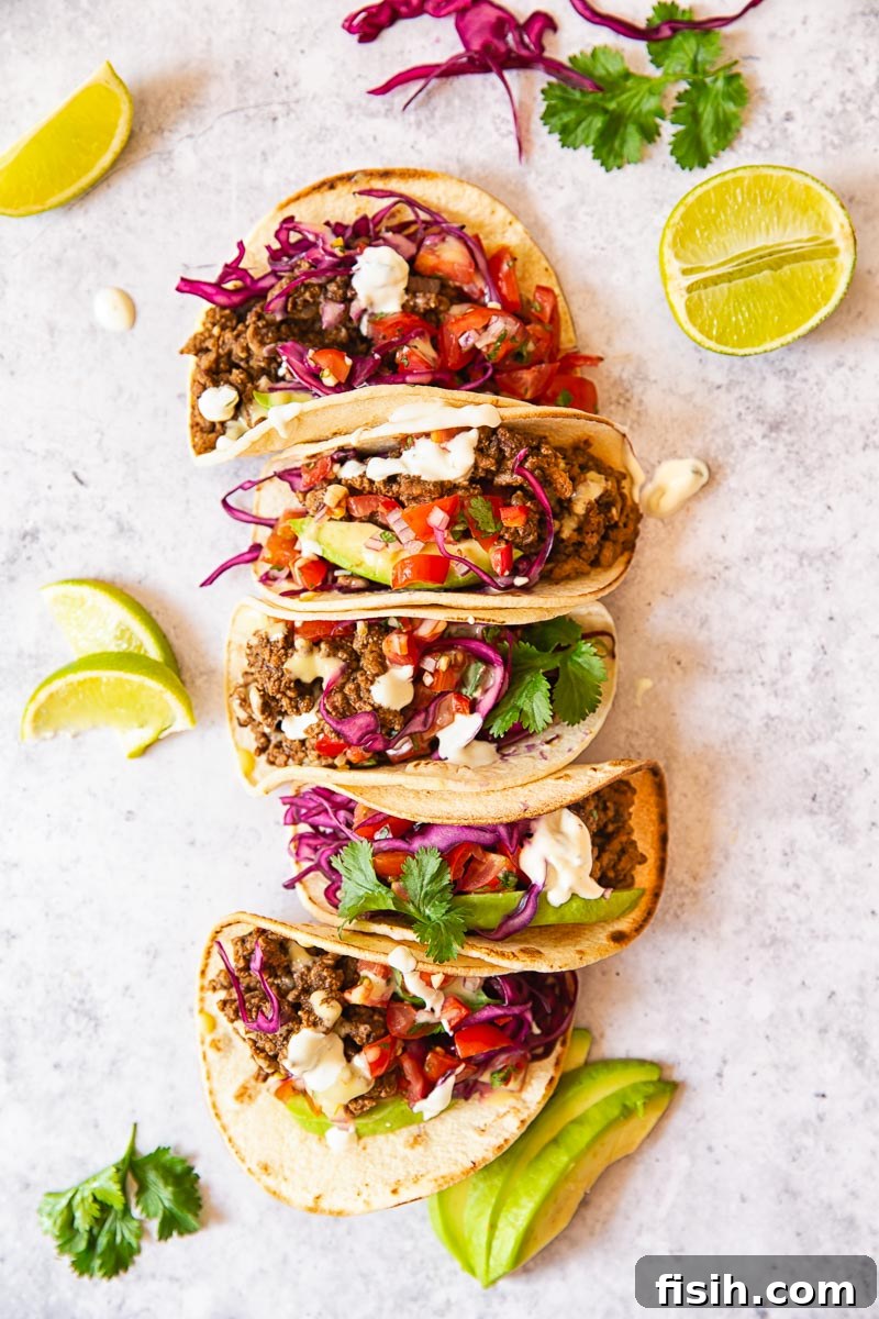 Delicious Ground Beef Tacos garnished with fresh salsa, ripe avocado slices, and a tangy red cabbage slaw, artfully arranged.