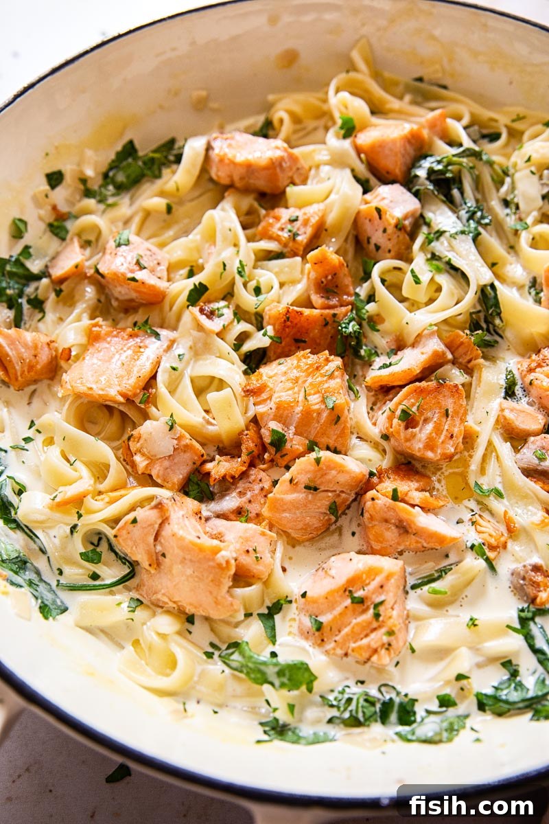 Salmon Pasta with greens in a white pan, ready to be served.