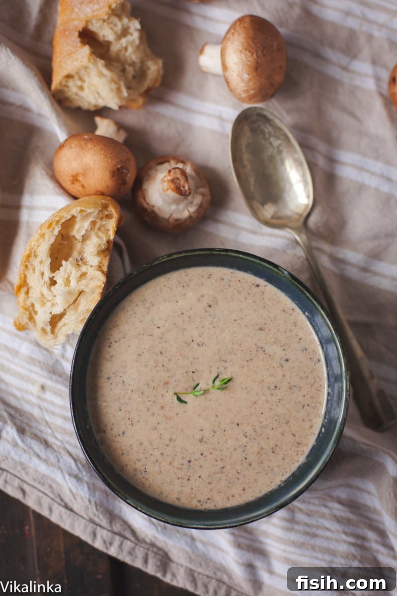 A close-up shot of a steaming bowl of creamy mushroom soup, garnished with fresh herbs and a swirl of cream, inviting a comforting culinary experience.