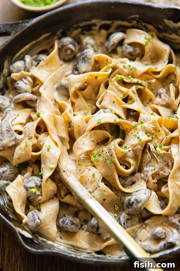 pan of mushroom stroganoff with a set of serving tongs