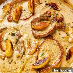 Pork chops and apples in creamy apple cider sauce in a cast iron pan