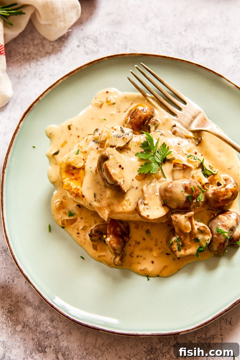 Creamy Garlic Mushroom Chicken 4 A serving of chicken breast with garlic mushroom sauce on a white plate, ready to be enjoyed.