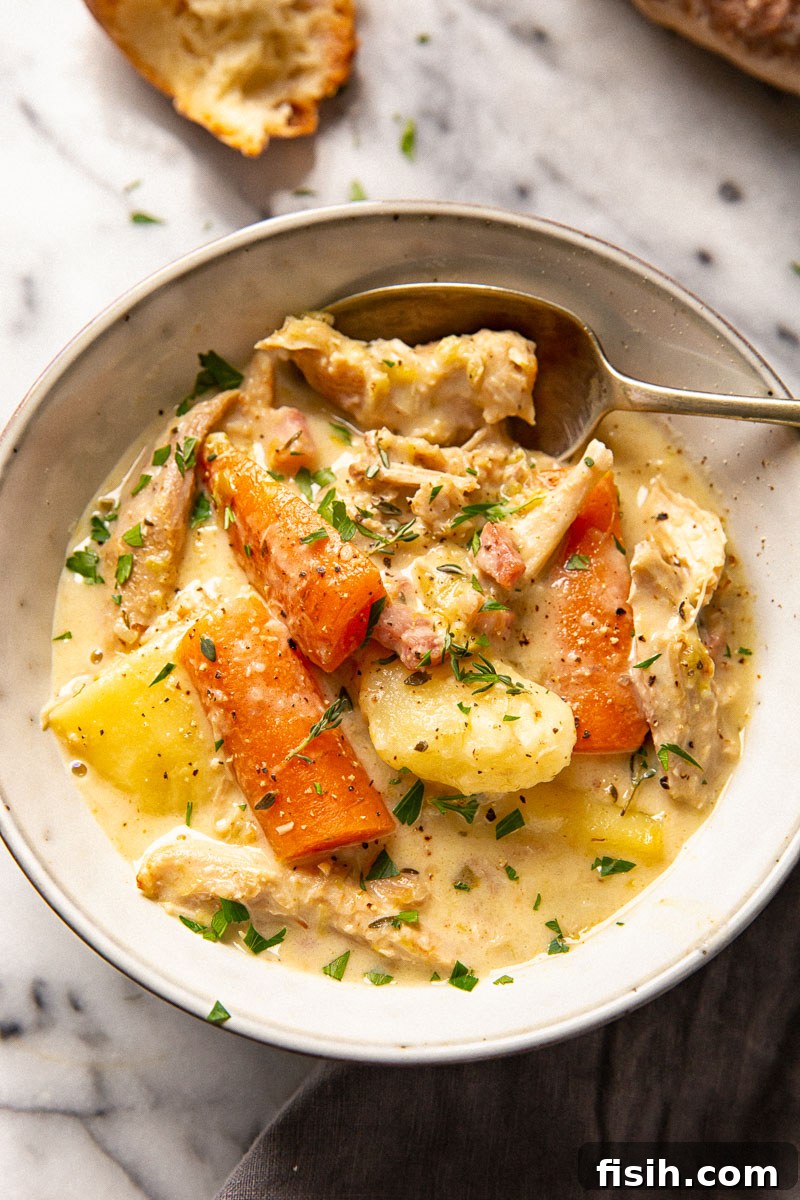 A bowl of creamy turkey stew with carrots and potatoes, garnished with fresh parsley, ready to be eaten
