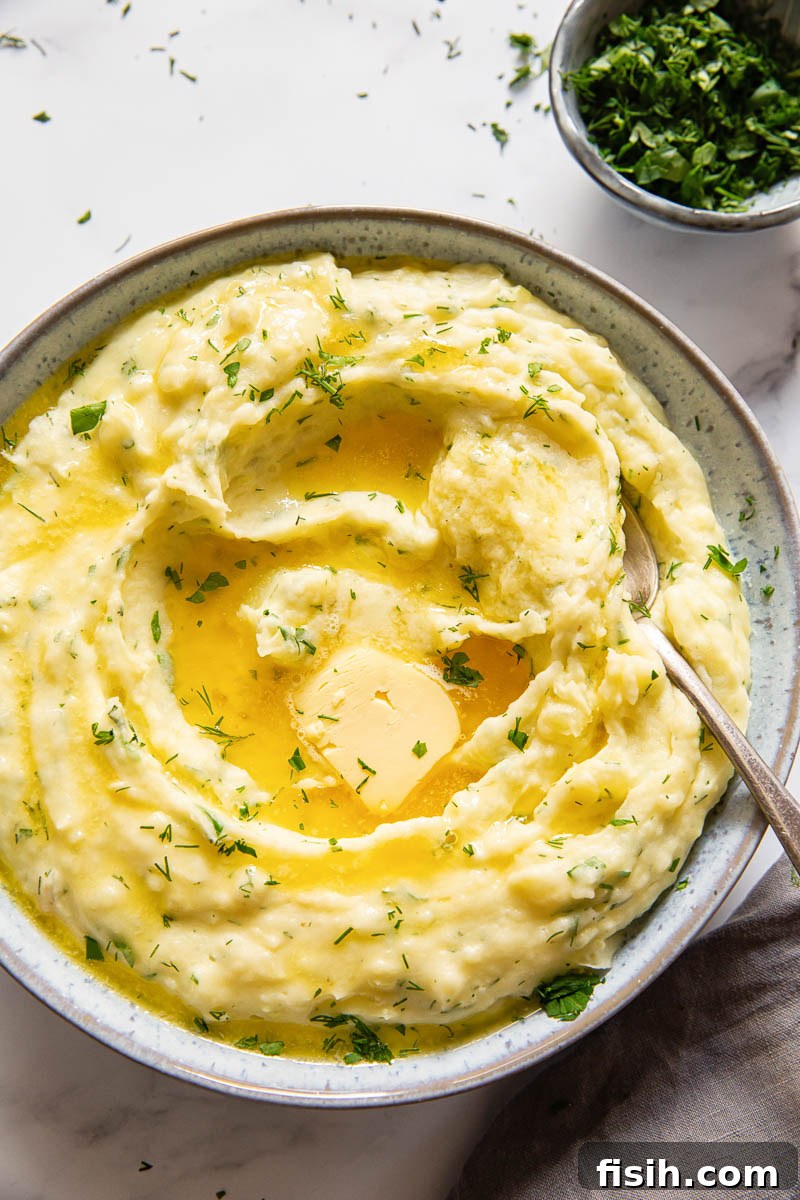 Savory Garlic Herb Mash 2 Herby mashed potatoes with melted butter in the center, garnished with fresh herbs.
