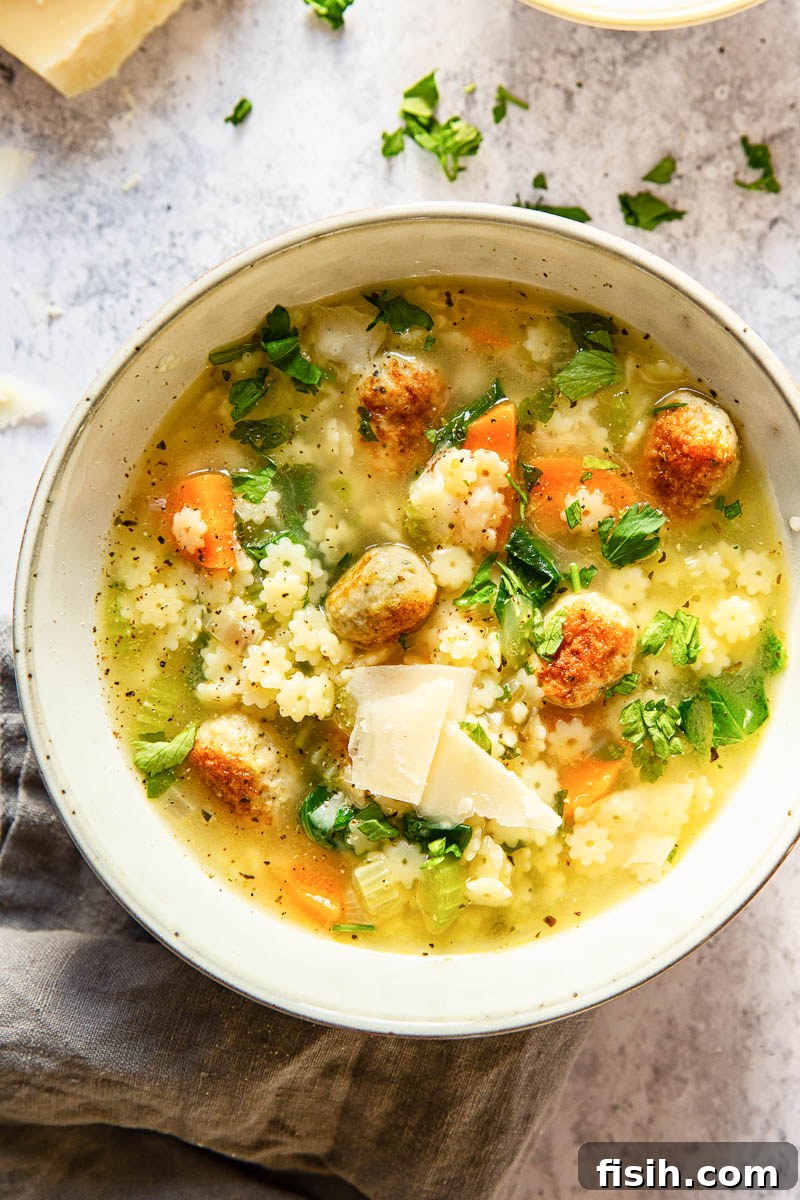 A steaming bowl of homemade Italian Wedding Soup, filled with golden meatballs, vibrant green spinach, and tiny star-shaped pasta, ready to be enjoyed.