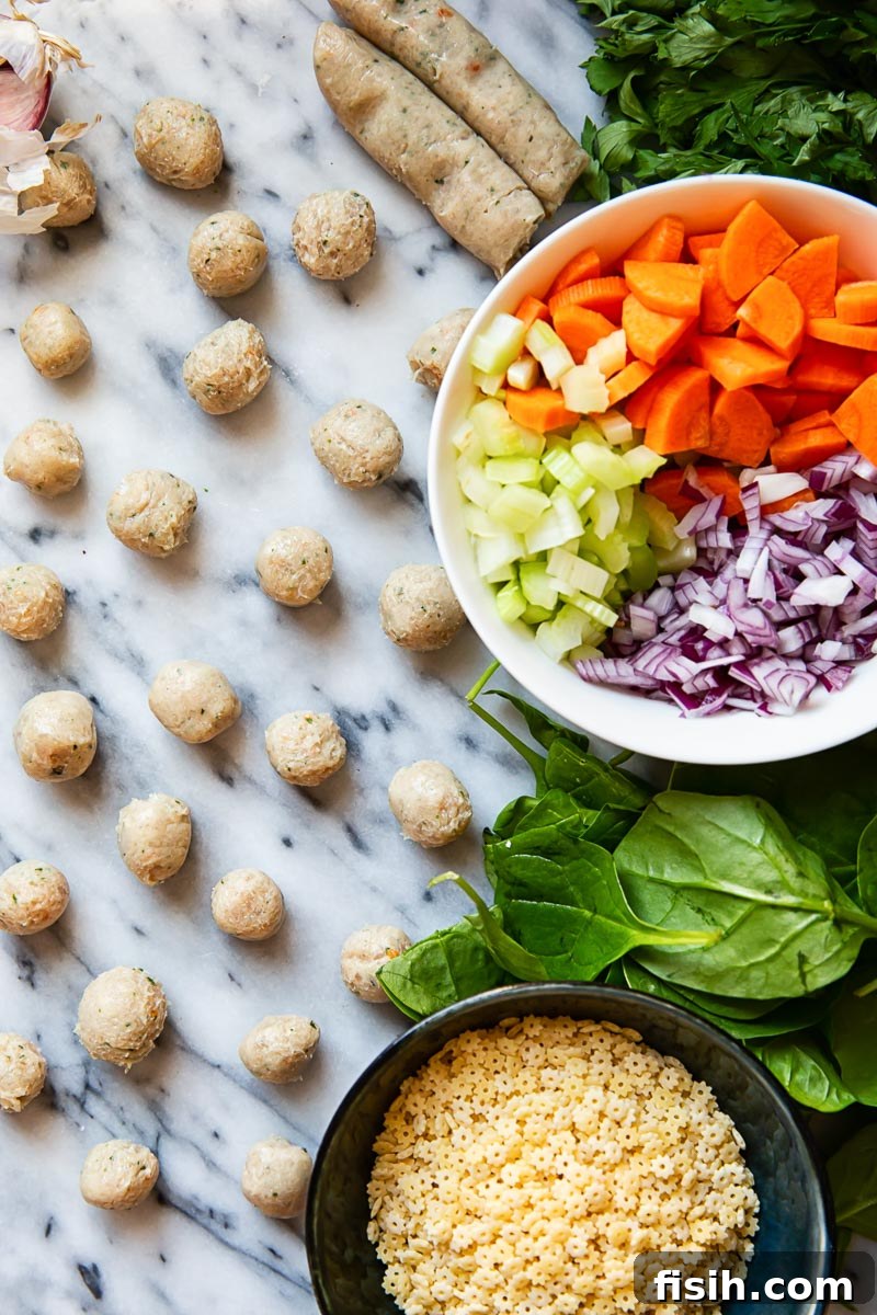 A vibrant flat lay of fresh ingredients for Italian Wedding Soup, including raw Italian sausages, carrots, celery, onion, garlic, spinach, and small pasta.