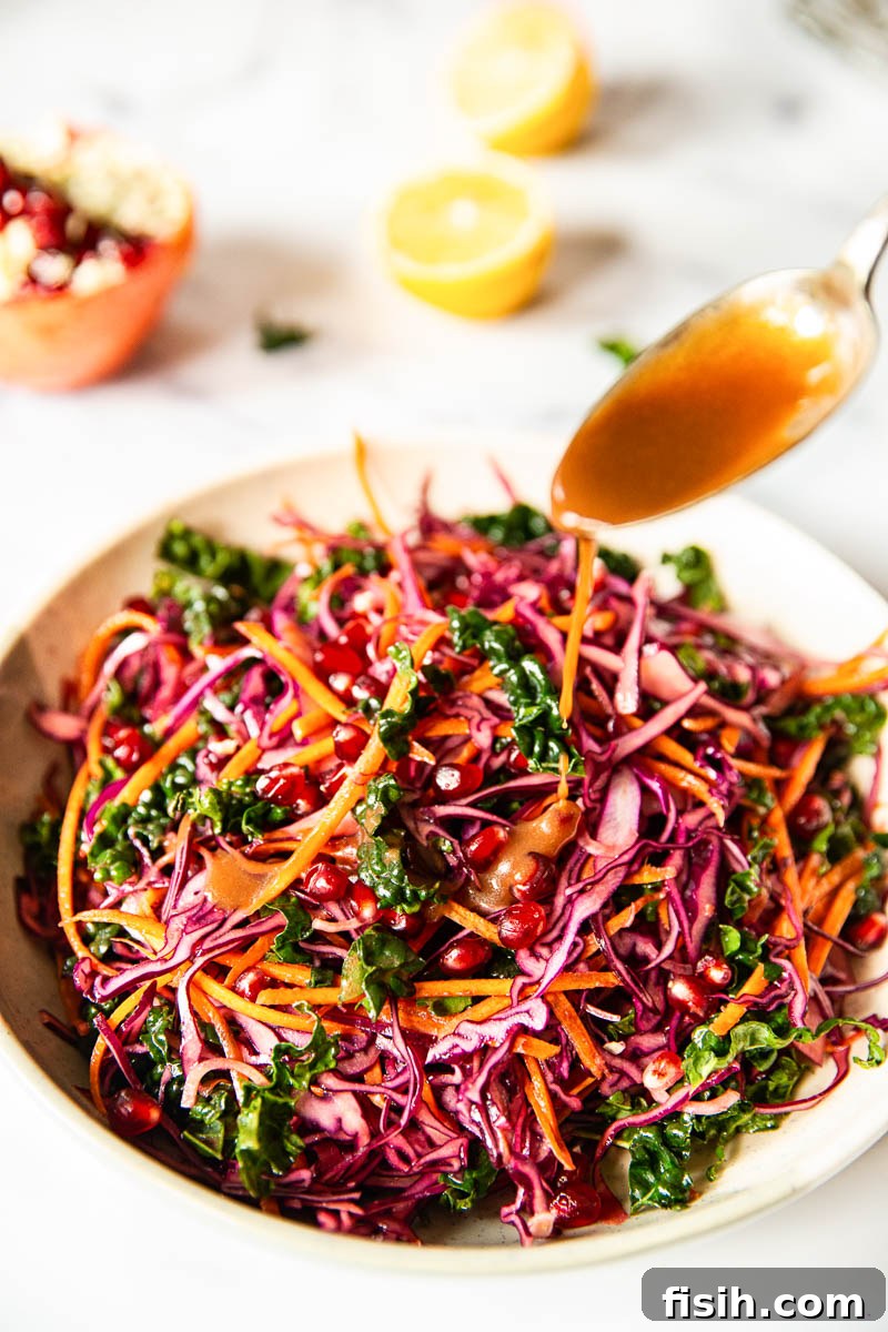 A close-up shot of the finished Red Cabbage Slaw with Carrots and Pomegranate, perfectly tossed with the zesty vinaigrette and ready to be served from a rustic bowl, highlighting its vibrant colors and textures.